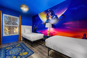 Ein Schlafzimmer mit zwei Betten, einer großen Wandmalerei, einem Fenster mit Jalousien und einem gemusterten Teppich.