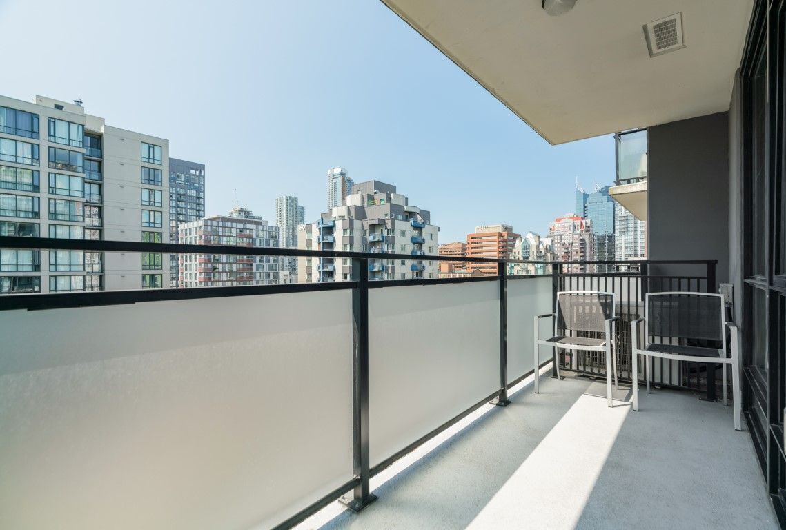 Un balcon offrant une vue sur le paysage urbain, avec des bâtiments modernes et un ciel dégagé.