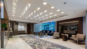 A modern lobby with a long, patterned carpet, a sofa area, and a TV screen. - Modern Studio Suite in Yaletown w/ Access to Pool (Vancouver)