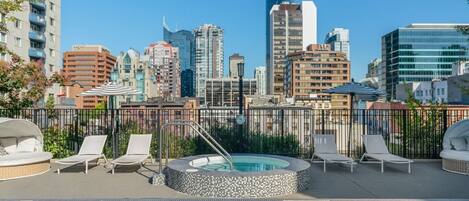 Une piscine sur le toit, dotée de chaises longues et d’un jacuzzi, le tout surplombant le panorama urbain.