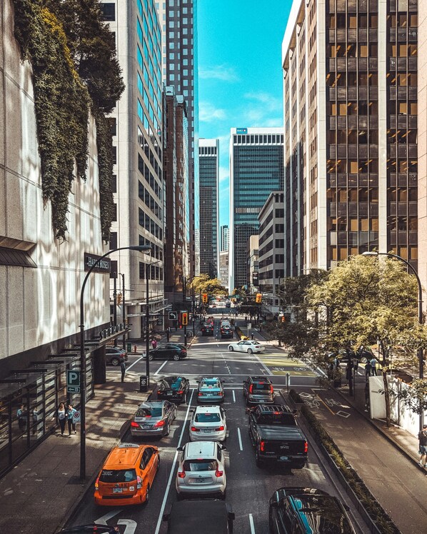 Una calle urbana concurrida, con edificios altos, un paso de cebra y varios vehículos, entre ellos taxis y automóviles.