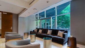 Een moderne zithoek met een grote bank, meerdere fauteuils en cilindrische bijzettafeltjes.