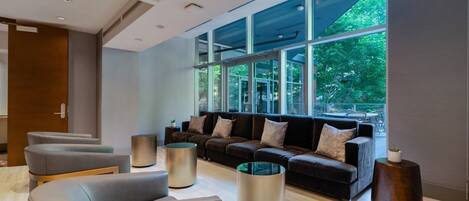 A modern lounge area with a large sofa set, multiple armchairs, and cylindrical side tables.