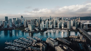 A cityscape with high-rise buildings, a marina with boats, and a bridge.