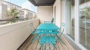 A balcony with a table and chairs, a metal railing, and a view of neighboring buildings. - Appartement calme et lumineux, terrasse et P privé (Balma)