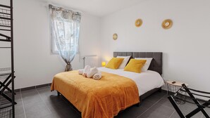 A bedroom with a bed, a ceiling fan, a window with curtains, and a small table with a lamp. - Appartement calme et lumineux, terrasse et P privé (Balma)
