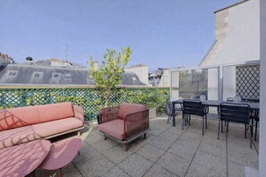 A rooftop patio with outdoor furniture, a small tree, and a view of the cityscape. - Cocoon with Eiffel Tower view (Paris)