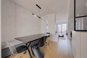 Une cuisine moderne avec des meubles blancs, une table à manger en bois et un four encastré.