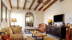 Ein Wohnzimmer mit Sofa, Sesseln, Couchtisch, Fernseher und Kamin.