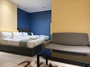 Een hotelkamer met een bed, een bank, een glazen salontafel en een blauwe wand.