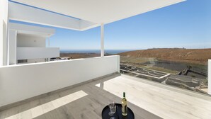 A modern balcony with a clear view of the landscape, a table with a bottle and glass, and a white interior. - Villa Papaya by Escape Home (Tías)