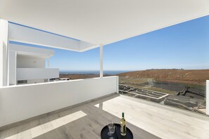 Ein moderner Balkon mit freiem Blick auf die Landschaft, ein Tisch mit Flasche und Glas sowie ein helles Interieur.