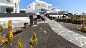 A modern multi-story house with a staircase leading to a glass balcony, surrounded by desert plants and a stone pathway. - Villa Papaya by Escape Home (Tías)