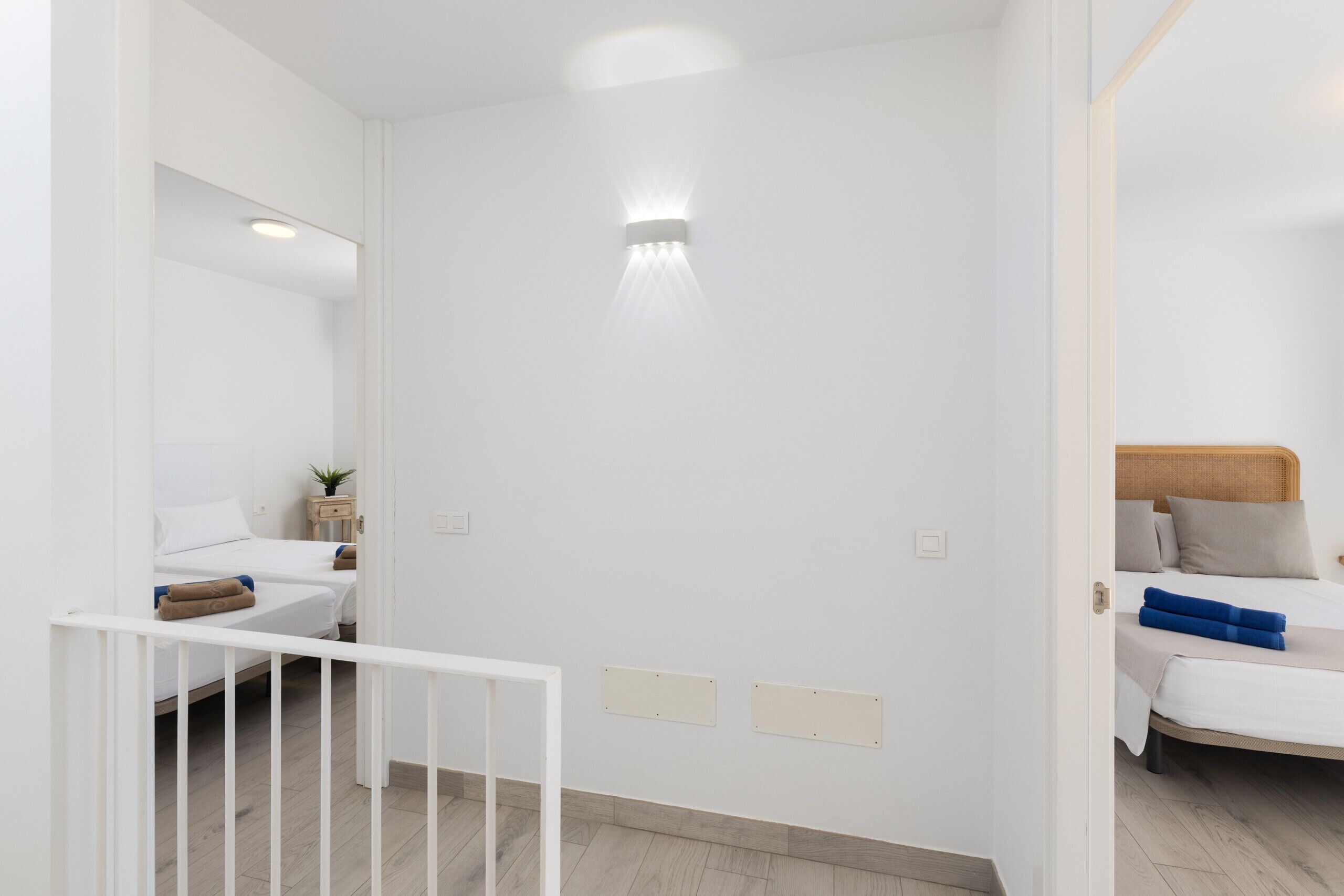 Een hotelkamer met een bed, een klein nachtkastje, een spiegel en een wandlamp.