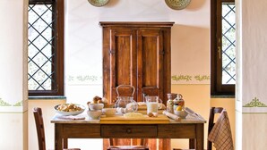 A dining area with a wooden table, chairs, and a kitchen counter. - Villa with pool surrounded by an olive grove (Assisi)