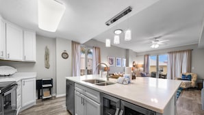 A modern kitchen with a large island, built-in appliances, and pendant lighting. - The Dunes 100 (Gulf Shores)