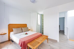 A bedroom with a bed, bedside tables, a bench, a wardrobe, and a door leading to another room. - Villa Mandarina by Escape Home (Tías)