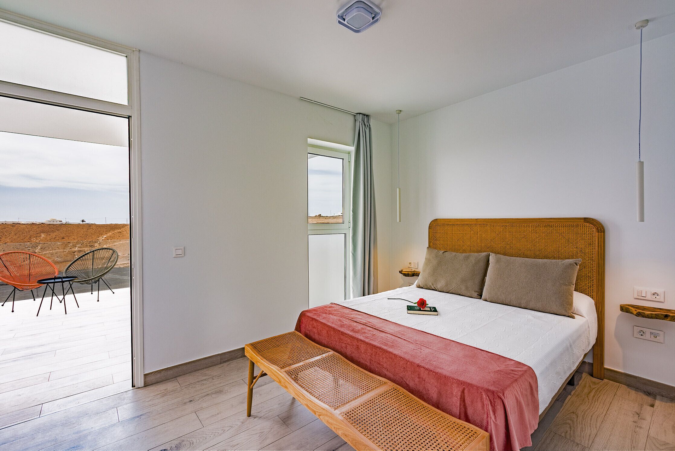 Een slaapkamer met een groot bed, een bankje, een raam en uitzicht op de omgeving.