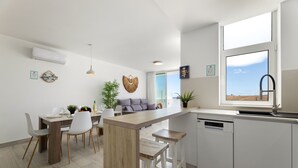 Een moderne keuken met een centraal eiland, witte kasten en een groot raam met uitzicht.