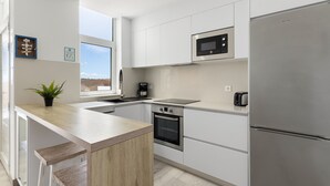 Een moderne keuken met witte kasten, een roestvrijstalen koelkast, een magnetron en een inbouwoven.