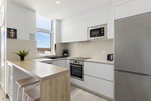 A modern kitchen with white cabinetry, a stainless steel refrigerator, a microwave, and a built-in oven. - Villa Pitaya by Escape Home (Tías)