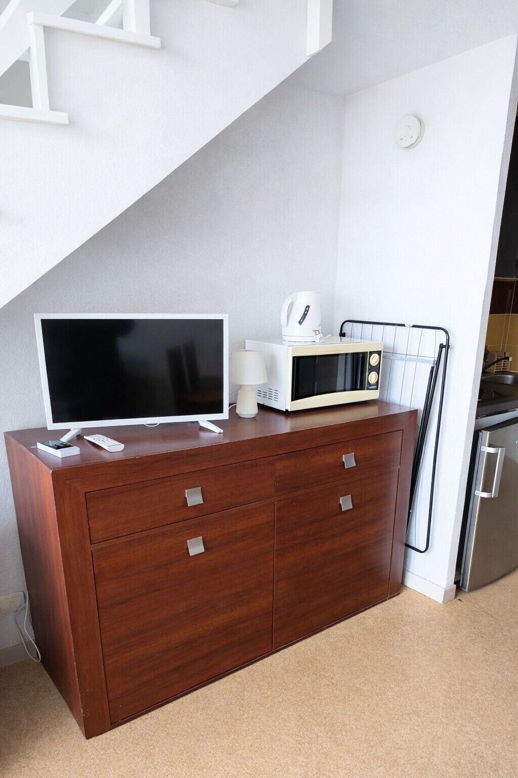 Un aparador de madera con un televisor de pantalla plana, una cafetera y un microondas.