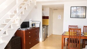 A loft-style room with a staircase, a kitchenette, a dining area, and a sofa. - LVAM - Appartement Résidence St Clair - Piscine - 4 personnes - Cap d'Agde (Le Cap D'Agde)