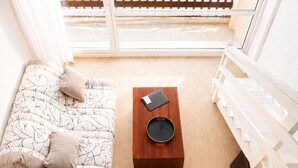 A balcony with a wooden railing, a sofa with cushions, a coffee table with a book and a pan, and a view of the outside. - LVAM - Appartement Résidence St Clair - Piscine - 4 personnes - Cap d'Agde (Le Cap D'Agde)