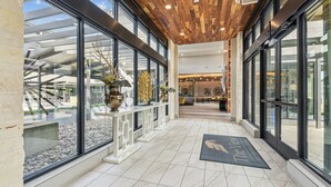 Un moderno vestíbulo de hotel con fachada de vidrio, techo de madera y un mostrador de recepción.