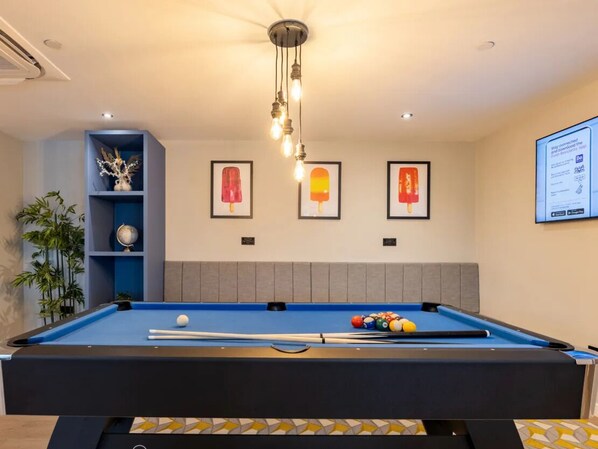 A pool table with balls, a ceiling fan, and framed pictures on the wall.