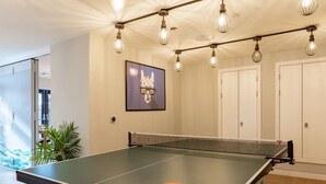 Ein Tischtennis-Tisch mit Schmetterlingslogo, umgeben von einer Decke mit freiliegenden Balken und Pendelleuchten.