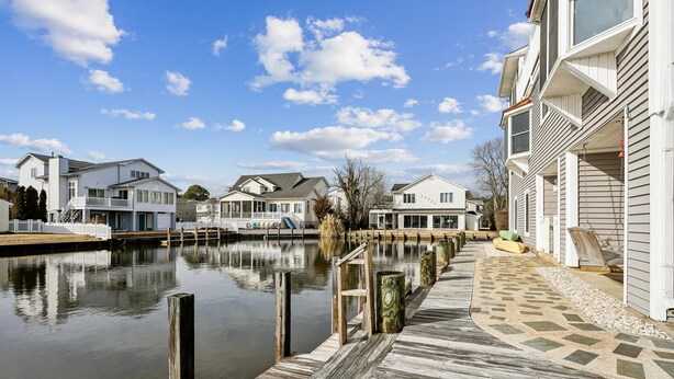 A waterfront property with a wooden dock, white houses, and a clear sky. - Waterfront 5 bedroom vacation retreat in South Bethany (South Bethany)