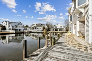 A waterfront property with a wooden dock, white houses, and a clear sky. - Waterfront 5 bedroom vacation retreat in South Bethany (South Bethany)