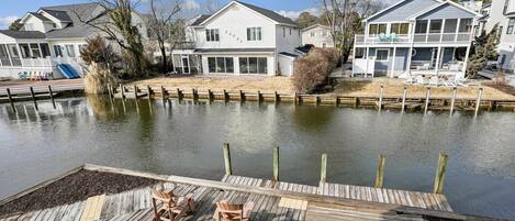 A waterfront property with a dock, wooden chairs, and houses with balconies.
