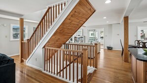 A modern interior with a wooden staircase, a kitchen area, and a dining space. - Waterfront 5 bedroom vacation retreat in South Bethany (South Bethany)