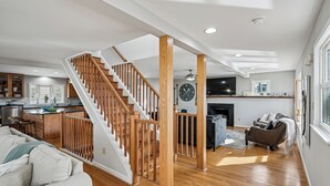 A spacious living area with a wooden staircase, a kitchen, and a fireplace. - Waterfront 5 bedroom vacation retreat in South Bethany (South Bethany)