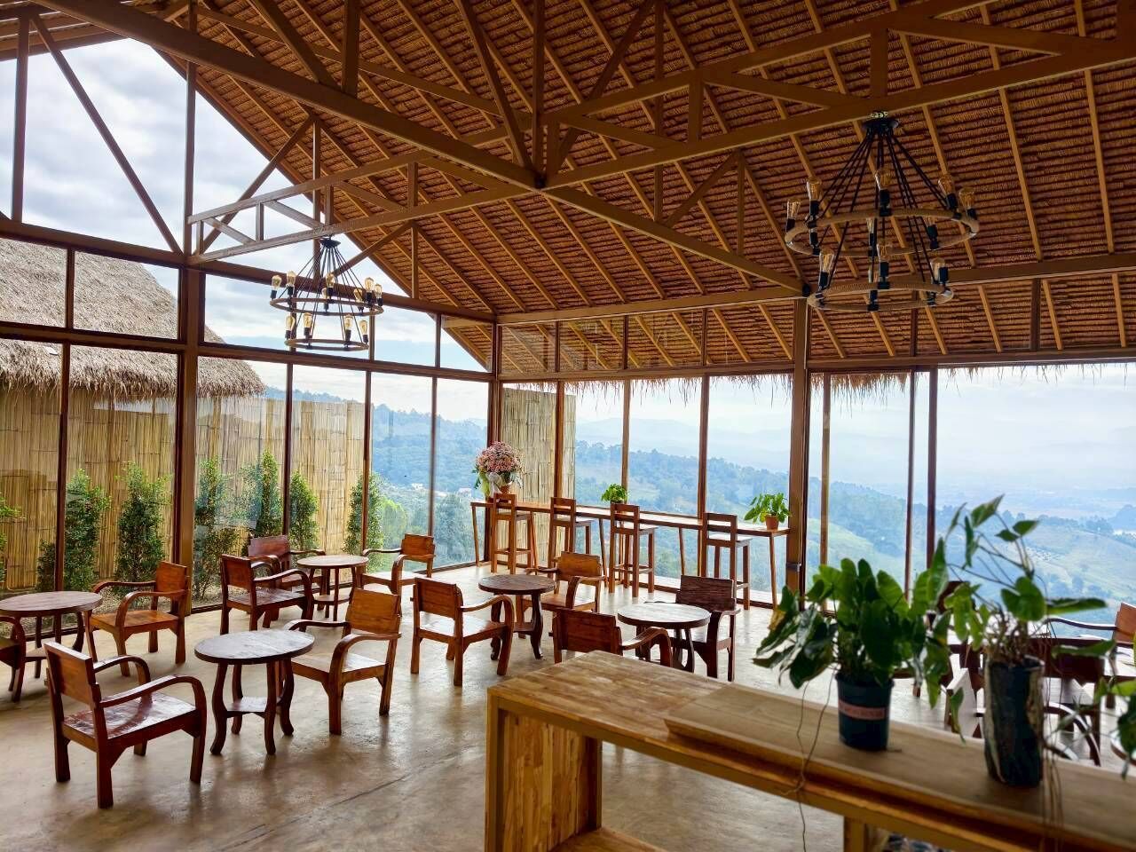 A spacious indoor area with wooden furniture and large windows offering a view of the landscape.