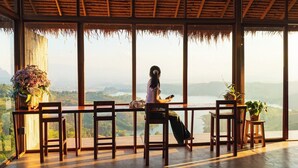 Ein Zimmer mit großen Fenstern, die einen schönen Ausblick bieten, Holzeinrichtung und einem Strohdach.