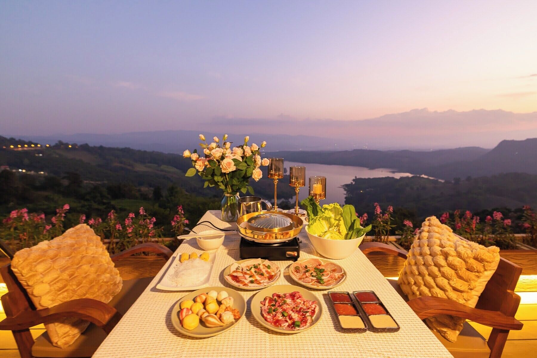 A table set with food and drinks, overlooking a scenic landscape.