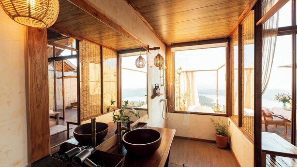 Ein traditioneller japanischer Raum mit Tatami-Böden, einem niedrigen Holztisch mit Schalen und Blick auf das Meer durch große Fenster.