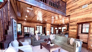 Un intérieur spacieux de chalet en bois, comprenant un salon, un coin repas et une cuisine.