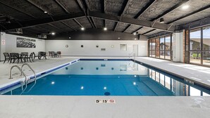 Piscina interior con una profundidad de 1,5 metros, rodeada de asientos y vistas al exterior.