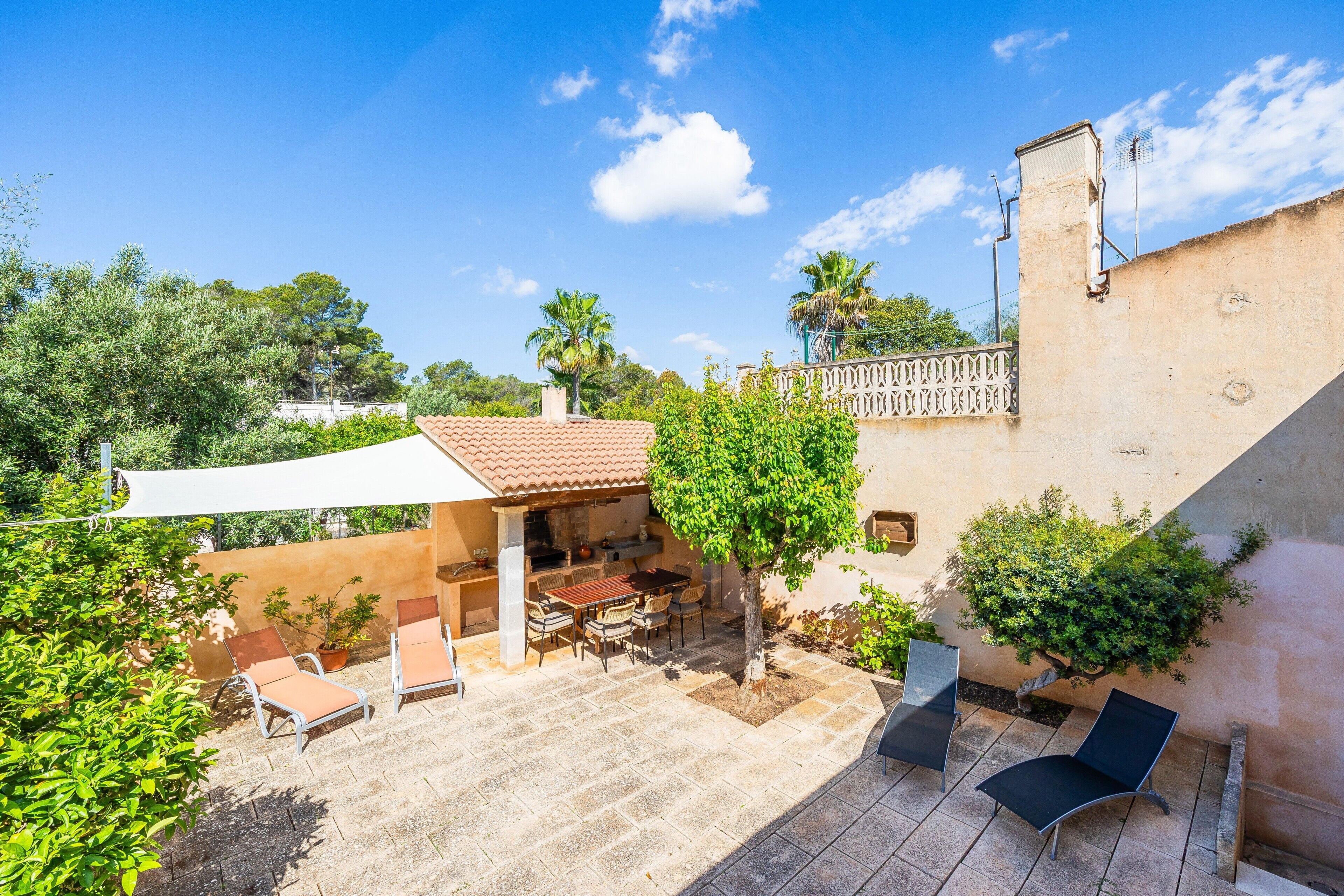 Une terrasse avec des meubles d’extérieur, un barbecue et un auvent blanc.