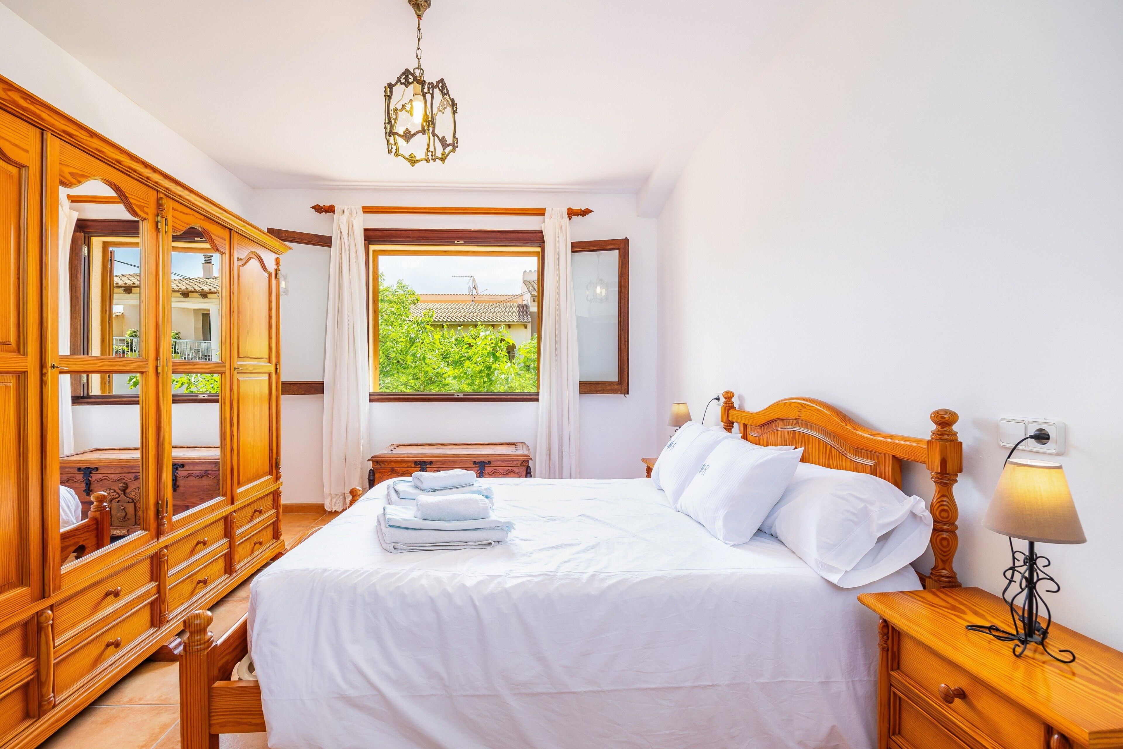 Une chambre avec un grand lit, une armoire en bois et une fenêtre donnant sur un beau paysage.