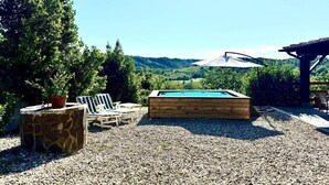 Area piscina con terrazza in legno, lettini e tavolino in pietra.