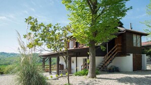 Una casa a due piani con facciata in legno, un portico coperto e una scala che conduce al piano superiore.