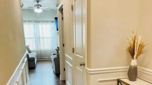 A hallway with wooden flooring, white walls, and a ceiling fan. - Cozy 4BR + Fast WiFi + Self Check-In + Near I-75 (McDonough)