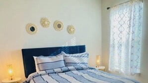 A bedroom with a bed, two bedside tables, and decorative wall art. - Cozy 4BR + Fast WiFi + Self Check-In + Near I-75 (McDonough)