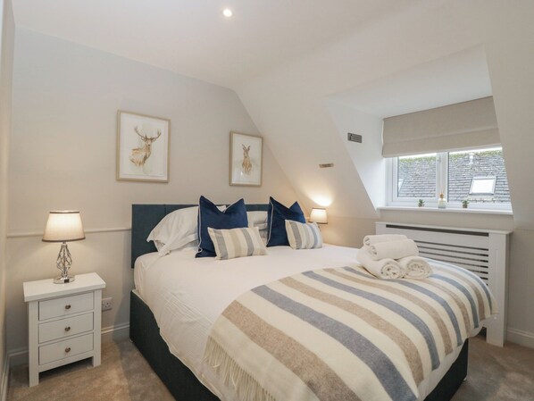 Een slaapkamer met een bed, nachtkastjes, een raam en kunstwerken aan de wanden.