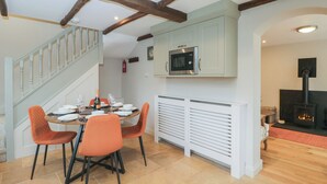 A dining area with a wooden ceiling, a staircase, a microwave, and a fireplace. - Paddock View (Cheltenham)